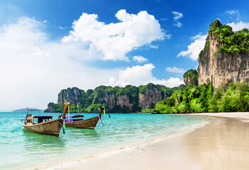 Thai traditional wooden longtail boat on tropical beach with limestone rock, Railay Beach in Krabi province., Thailand.