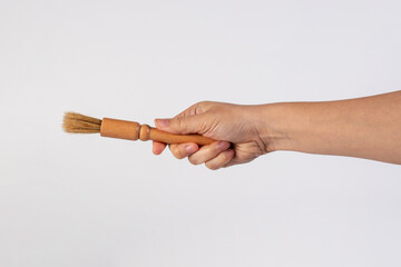 Hand using a wood little paintbrush isolated on a white background