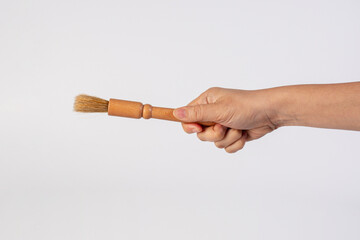 Hand using a wood little paintbrush isolated on a white background