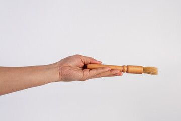 Hand using a wood little paintbrush isolated on a white background