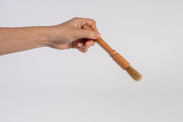 Hand using a wood little paintbrush isolated on a white background