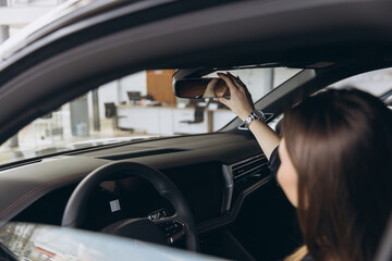 Customer Adjusting Rearview Mirror in New Car at Dealership