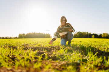 Young female farmer with a digital tablet inspects young plants in an agricultural field. Female...