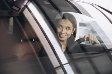 Businesswoman smiling and driving a new car in a dealership