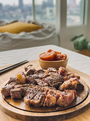 Beef steak medium rare with tomato on wooden plate.