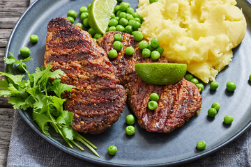 grilled beef cutlets with potato mash, green peas