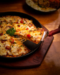 one sliced melted pizza from hot plate on wooden table. Pizza with mushroom, cheese, tomato, bacon and parmesan. Perfect for advertising or commercial purpose