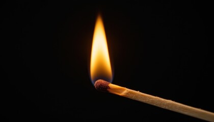 A close up of a lit matchstick with vibrant flames against a dark background.