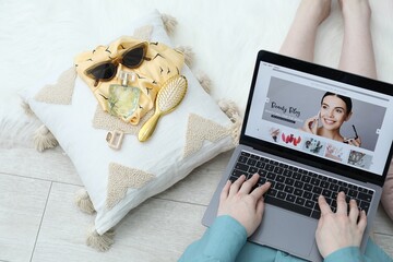 Blogger using laptop with beauty blog web site on floor indoors, above view