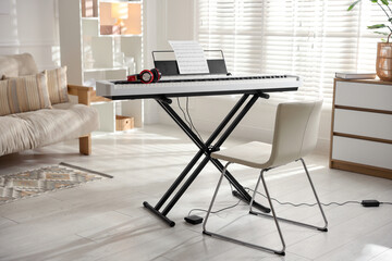 Synthesizer with music sheet, headphones and chair indoors