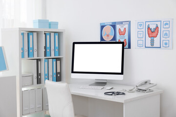 Clipboard, pen, computer, telephone and stethoscope on desk in doctor's office
