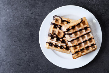 Belgian Waffles with chocolate on black slate background. Top view. Copy space