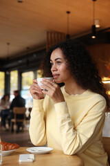 Woman enjoying her aromatic coffee at table in cafe