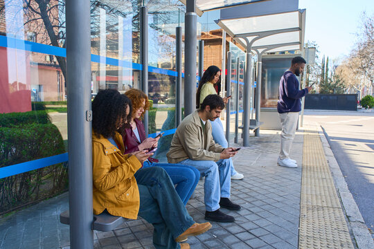 People using smartphones while waiting at bus stop