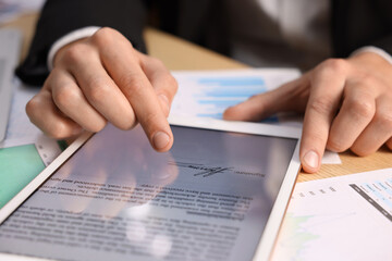 Electronic signature. Man using tablet at table, closeup