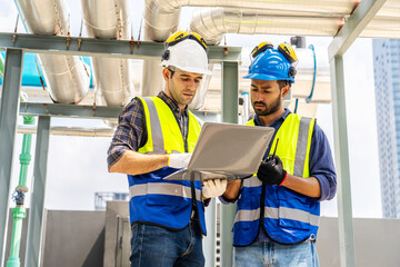 Collaboration, Two young construction workers discuss plans while reviewing blueprints on a...