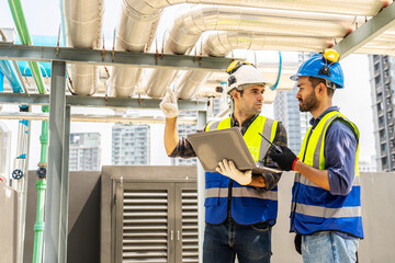 Collaboration, Two young construction workers discuss plans while reviewing blueprints on a...