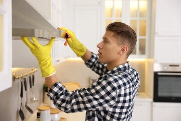 Man cleaning kitchen hood with rag at home