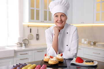 Professional pastry chef with desserts at table in kitchen
