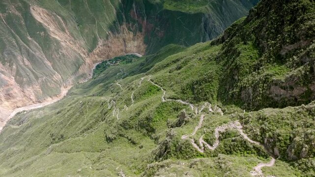 Drone shot from the beginning of the path in Cabanaconde, revealing the entire descent toward Sangalle, with the vast landscape of the Colca Canyon and the lush Oasis of Sangalle in the distance.