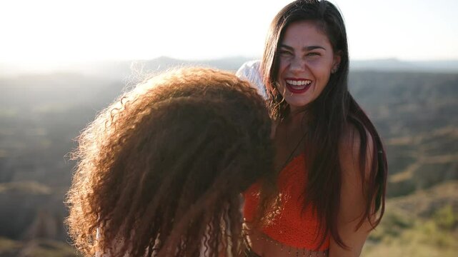 Two smiling women laughing together at sunset in desert canyon