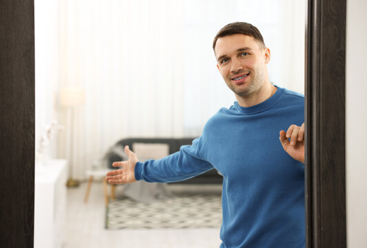 Cheerful man welcoming guests to his apartment. Space for text