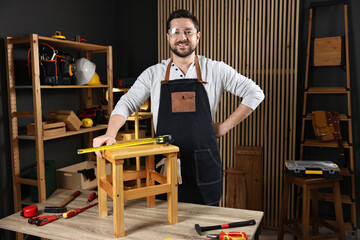 Professional repairman with wooden stool and tools in workshop
