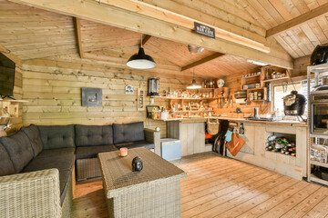 A warm and inviting interior of a rustic cabin featuring a kitchen area, comfortable seating, and wooden accents, perfect for relaxation and gatherings.