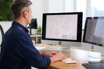 Engineer working with digital drawings at table in office