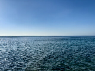Obraz premium calm sea under bright clear sky with copy space. solid blue background. minimalist sea background. straight lines. nature balance. deep