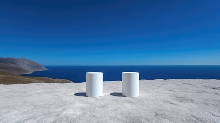 Two white cylinders on a cliff overlooking the sea