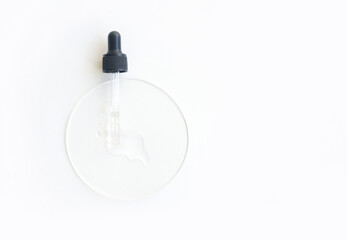 Transparent serum dropper on white surface with clear liquid for skincare and beauty treatments.
