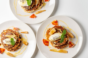 Cottage cheese pancakes with cream cheese, orange, honey and mint on a white plate and background. Healthy, dietary breakfast. Top view