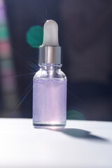 Glowing bottle of purple liquid serum with dropper lid and bokeh light effects in sunlight.