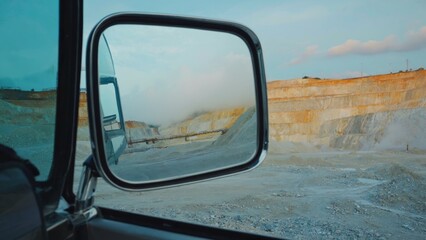 Reflection of quarry and road in side mirror.