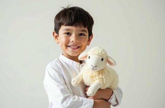 Happy boy holding soft toy lamb against neutral background. Eid al-Adha - Powered by Adobe