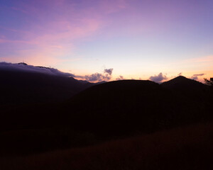 Early morning light paints the sky in soft purple and orange over Mount Tapyas, Coron, Palawan. Silhouettes of hills and clouds complete this tranquil sunrise view.