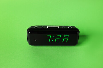 Digital alarm clock showing 7:28 o'clock on green background