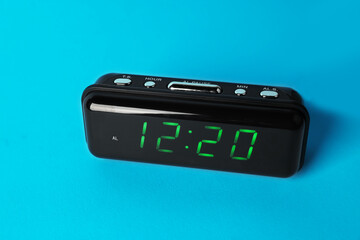 Digital alarm clock showing 12:20 o'clock on light blue background