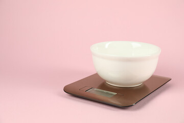 Electronic kitchen scale with bowl on pink background. Space for text