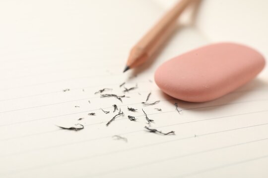 Eraser, pencil and scraps on lined notebook sheet, closeup. Space for text