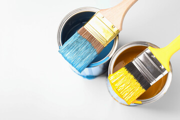 Cans of paint and brushes on light background, top view. Space for text