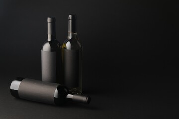 Bottles of wine on black background, space for text
