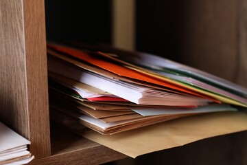 Different paper envelopes on wooden shelf in post office, closeup