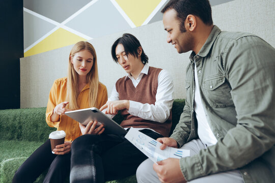 Marketing team analyzing data and working on digital tablet and documents