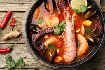 Delicious seafood soup in bowl on wooden table, flat lay