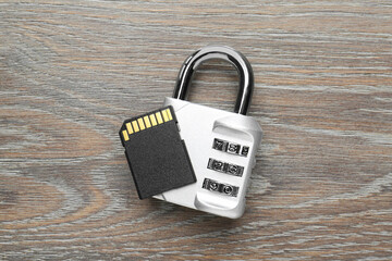 SD memory card and combination padlock on grey wooden table, top view