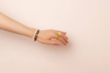 Fototapeta premium Handcrafted rings and bracelets on a female hand in front of beige background.