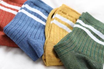 Different soft socks on white blanket, closeup