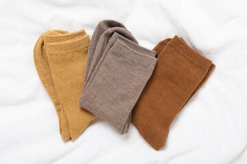 Different soft socks on white blanket, top view